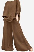 Brown wide leg pants with pockets styled with a loose brown top and rolled sleeves.