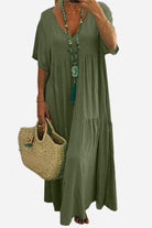 Olive green V-neck two-tiered maxi swing dress with loose sleeves and flowing silhouette, worn with beaded necklace and straw handbag.