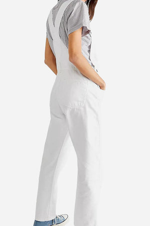 White denim-look tapered-leg adjustable bib overalls with pockets worn by woman viewed from back