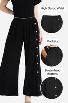 Black wide leg pants with high elastic waist, side buttons, and pockets, styled with a black top