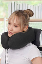 Woman using black memory foam neck pillow from Travel Comfy Kit for comfortable travel rest