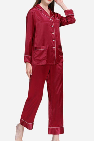 Woman wearing long sleeve button-up mulberry silk pajamas in deep red with white piping