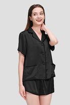 Woman wearing black 100% mulberry silk hemd trimmed short-sleeve pajama set with shorts