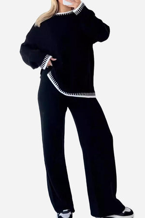 Woman wearing black Chic Contrast Stitch travel set with white stitching on cuffs, neckline, and hem, styled for casual comfort and travel.