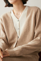 Woman wearing a beige single-breasted cashmere wool cardigan with white inner shirt and gold necklace