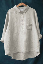 Light beige vintage linen shirt with half-button front and chest pocket hanging on wooden hanger