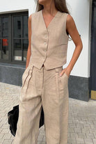 Woman wearing eco chic linen blend beige sleeveless vest and wide-leg pants two-piece outfit outdoors