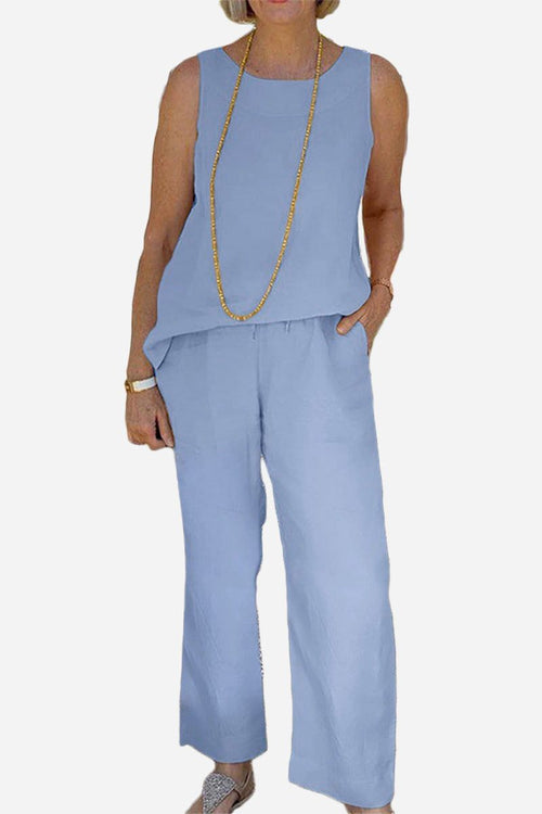 Woman wearing light blue sleeveless sleek silhouette coordinated set with wide-leg pants and long necklace