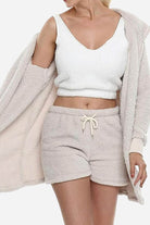 Woman wearing Cloud Soft 4-Piece Collection cozy beige shorts, white crop top, and matching plush cardigan.