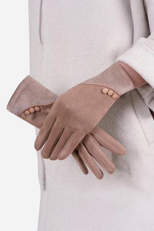 Pair of brown SmartTouch suede gloves with button detail worn on hands against a beige coat background