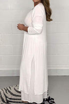 Woman wearing white Urban Chic V-Neck Split Top two-piece set with long sleeves and side splits, standing against a white brick wall.
