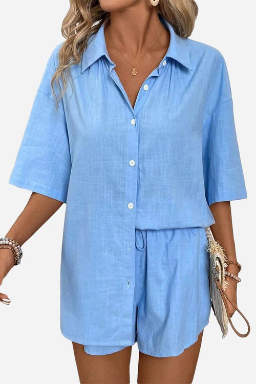 Woman wearing a light blue coastal linen cotton two-piece set with button-up shirt and shorts.