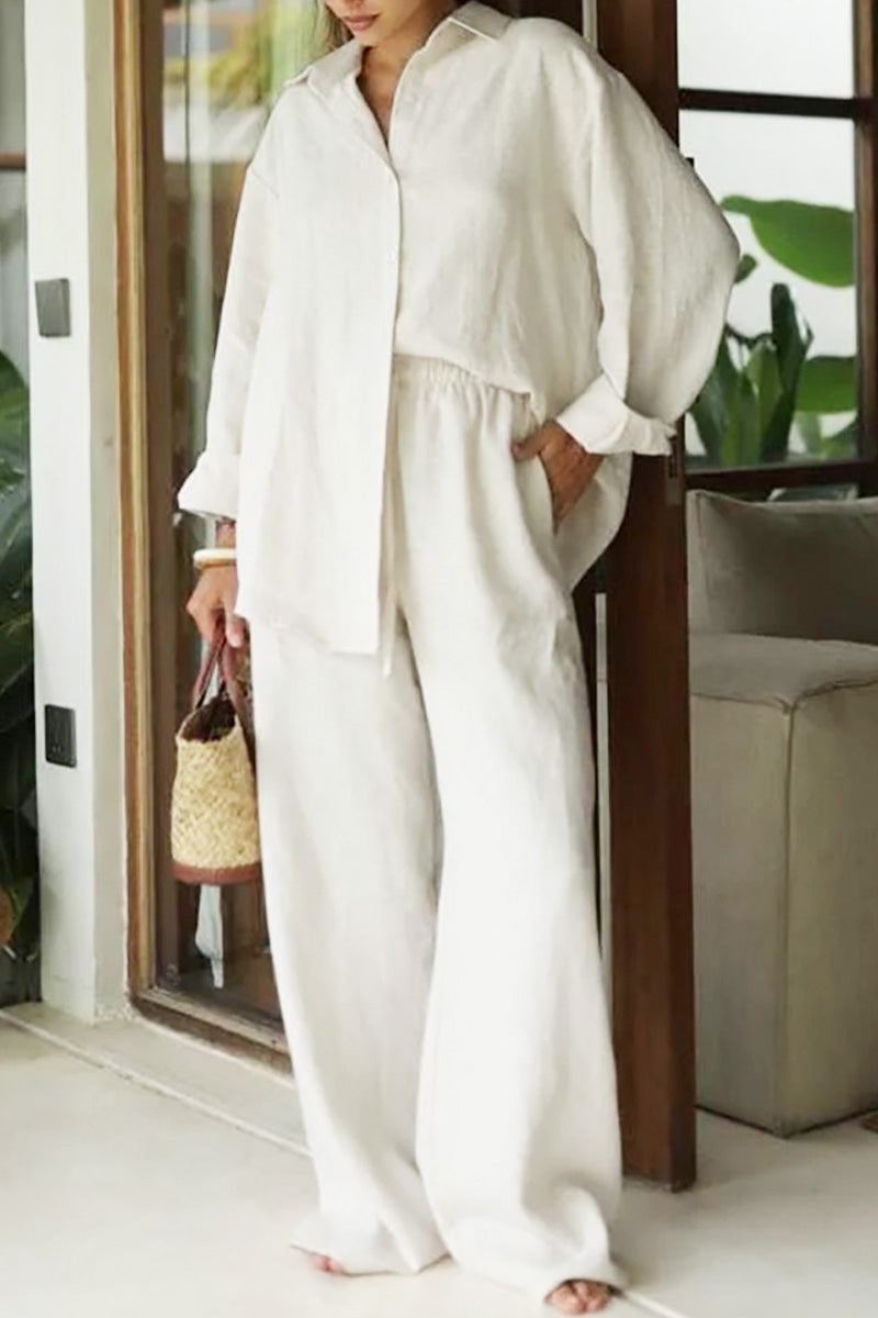 woman wearing white 100% cotton Wanderlust two piece set with long sleeves and wide pants indoors carrying woven bag
