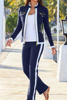 Woman wearing navy sleek contrast zip two-piece set with white side stripes and gold zipper details outdoors