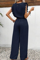 Back view of woman wearing elegant two-piece set with lace detail in navy blue, featuring ruffled sleeves and wide-leg pants