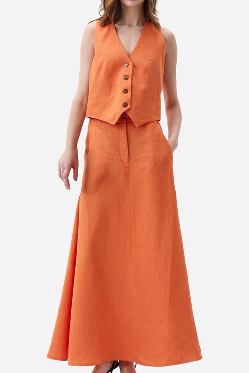 Woman wearing a sunset orange cotton-linen blend sleeveless vest and flowing skirt two-piece set.