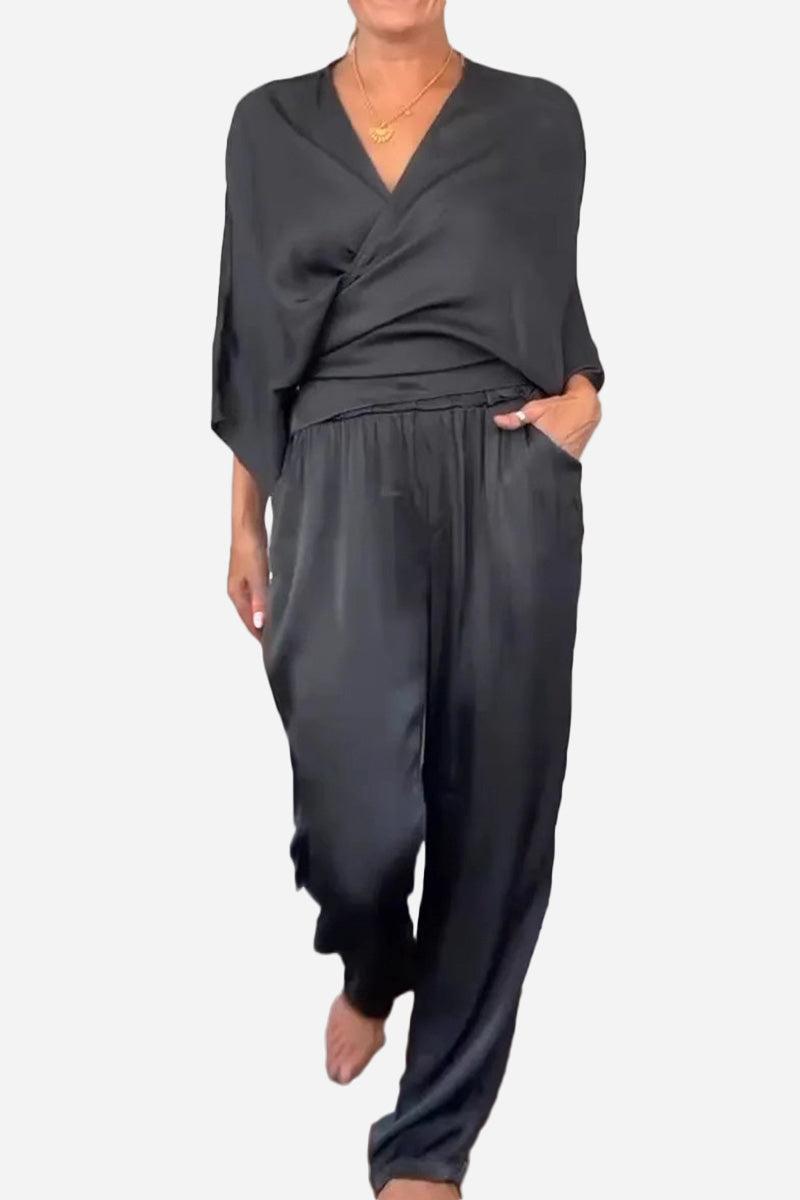 Woman wearing black Satin Wrap Lounge two-piece set with V-neck top and relaxed pants