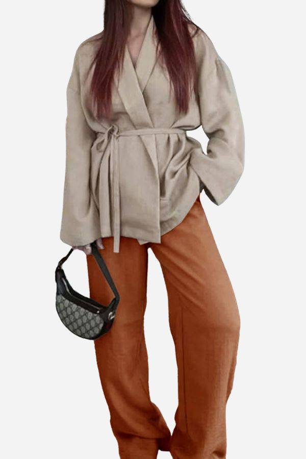 Woman wearing a beige belted top and rust-colored wide-leg pants from a versatile mix-match lounge-to-travel set with a black handbag.