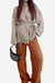 Woman wearing a beige belted top and rust-colored wide-leg pants from a versatile mix-match lounge-to-travel set with a black handbag.