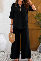 Woman wearing black wrinkle-free wide leg pants and button-front top set with three-quarter sleeves holding a woven handbag