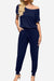 Woman wearing a navy blue Moonlit Rome Off-Shoulder jumpsuit with short sleeves and tapered legs, featuring a relaxed fit and drawstring waist.