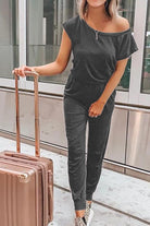 Woman wearing Moonlit Rome Off-Shoulder jumpsuit with suitcase in modern indoor setting