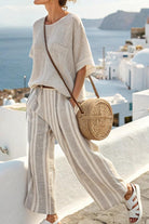 Woman wearing Coastal Comfort Linen two-piece set with striped wide-leg pants and loose top by the seaside.