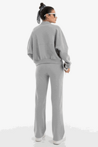 Woman wearing The Voyager Zip Set in light gray, featuring a relaxed zip-front sweatshirt and wide-leg joggers with pockets, styled for comfort and travel.