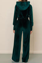 Back view of dark green velour tracksuit with cropped hoodie and high-waist pants on model against neutral background