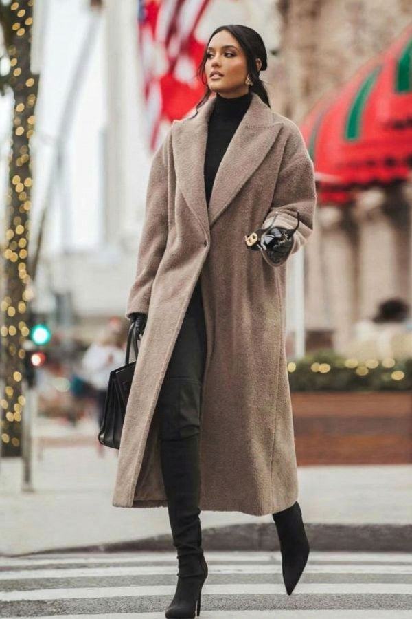Woman wearing oversized teddy coat in longline silhouette with drop shoulders and lapels walking in city street