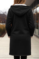 Black warm toggle button hooded coat with sherpa lining and faux suede exterior, mid-thigh length winter outerwear.