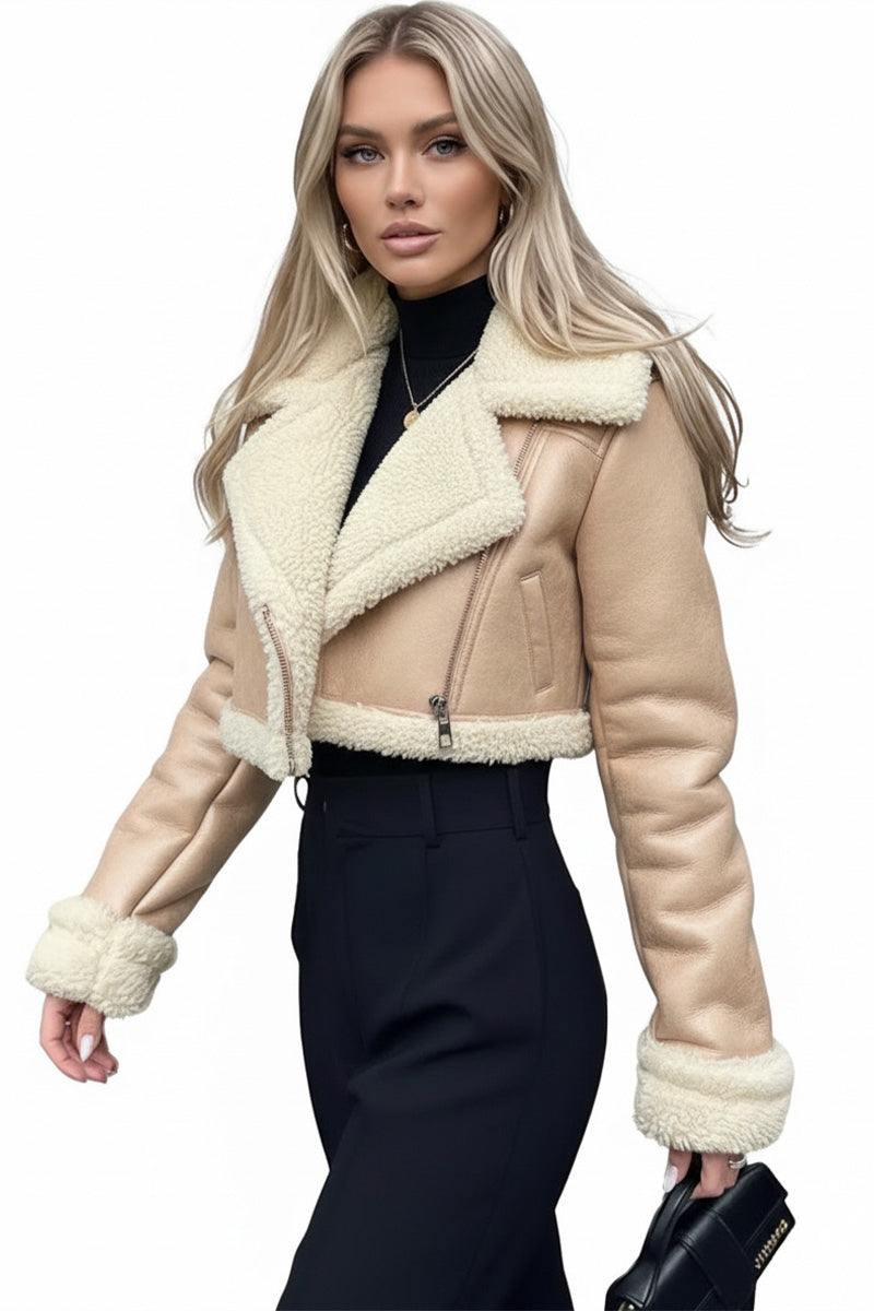 Woman wearing a beige cropped faux leather sherpa jacket with cream trim and black pants