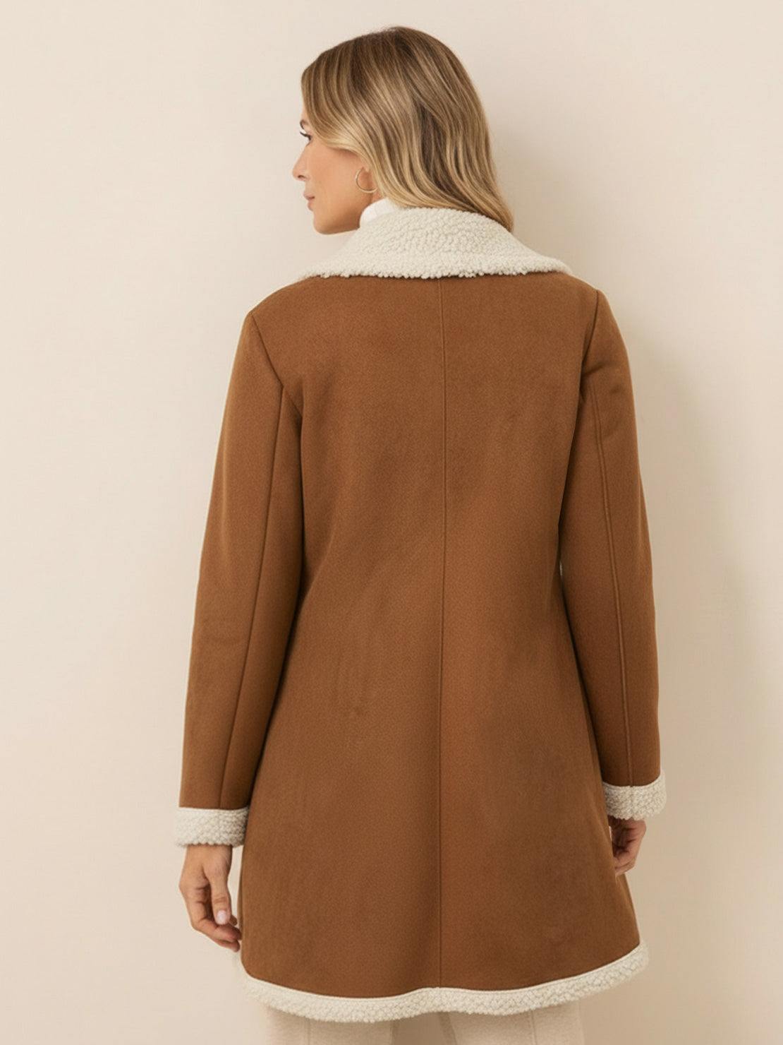 Woman wearing a relaxed mid-thigh faux suede sherpa coat with contrast trim and side pockets