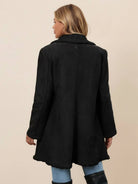 Woman wearing a mid-thigh faux suede sherpa coat with double-breasted front and contrast sherpa trim