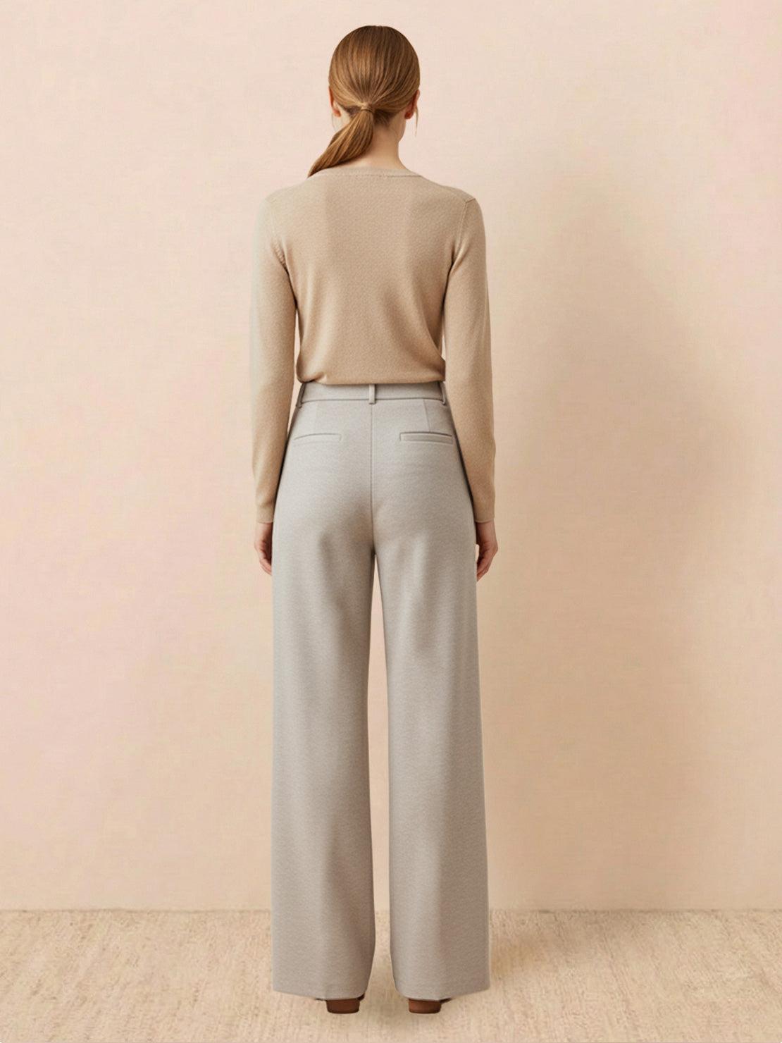 Woman wearing beige thermal wool blend trousers with wide-leg cut and elastic back waist standing against neutral background