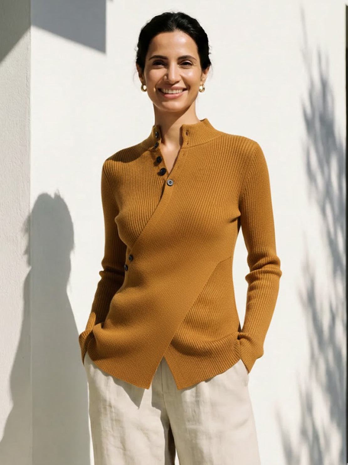 Woman wearing an asymmetric wrap ribbed knit top with diagonal button closure and flared cuffs