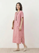 Woman wearing 100% linen pocket midi dress with short sleeves and side slits standing outdoors
