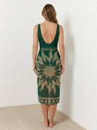 Deep-V swimsuit with ruched bust and waist, gold shell detail, wide straps, low back, and sheer sun-print sarong tied at hip