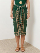 Deep-V swimsuit with ruched bust and waist, wide straps, low open back, and sheer celestial print sarong tied at hip