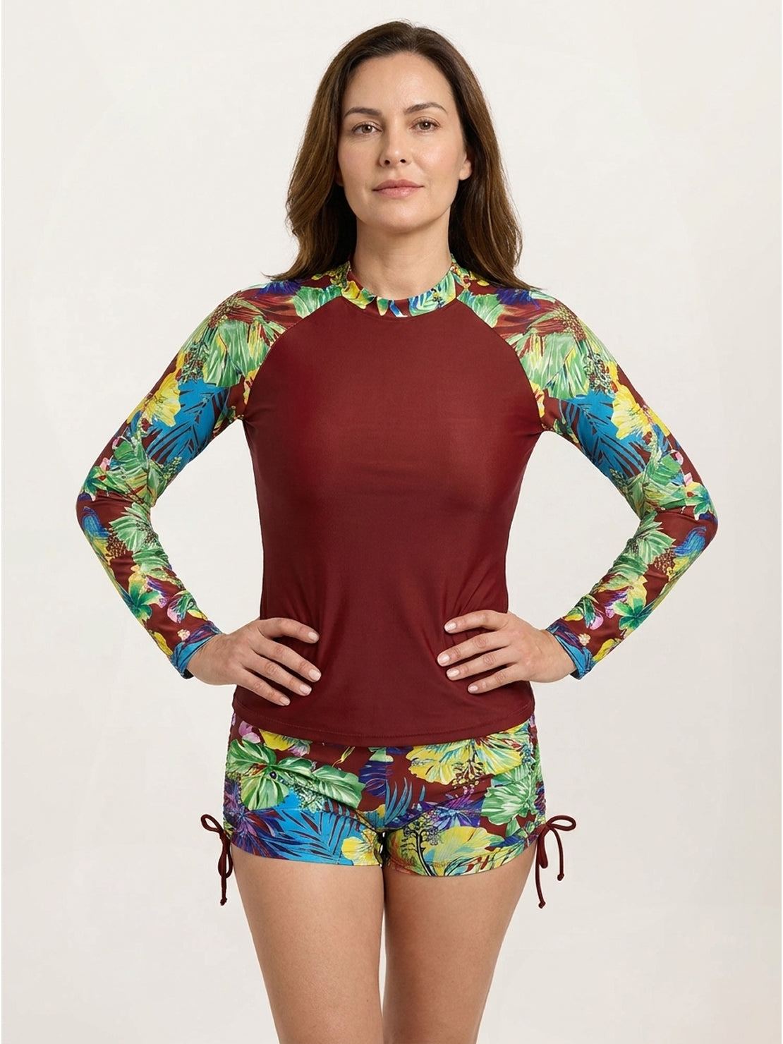Two-piece tropical print rash guard set with high neck, long sleeves, and boy-cut swim shorts with hip ties.