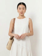 Woman wearing a cotton-linen summer midi dress with tiered skirt and relaxed drop-waist silhouette in natural fabric texture