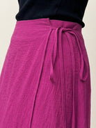 Woman wearing asymmetrical wrap maxi skirt with side tie closure and asymmetric hem in lightweight fabric