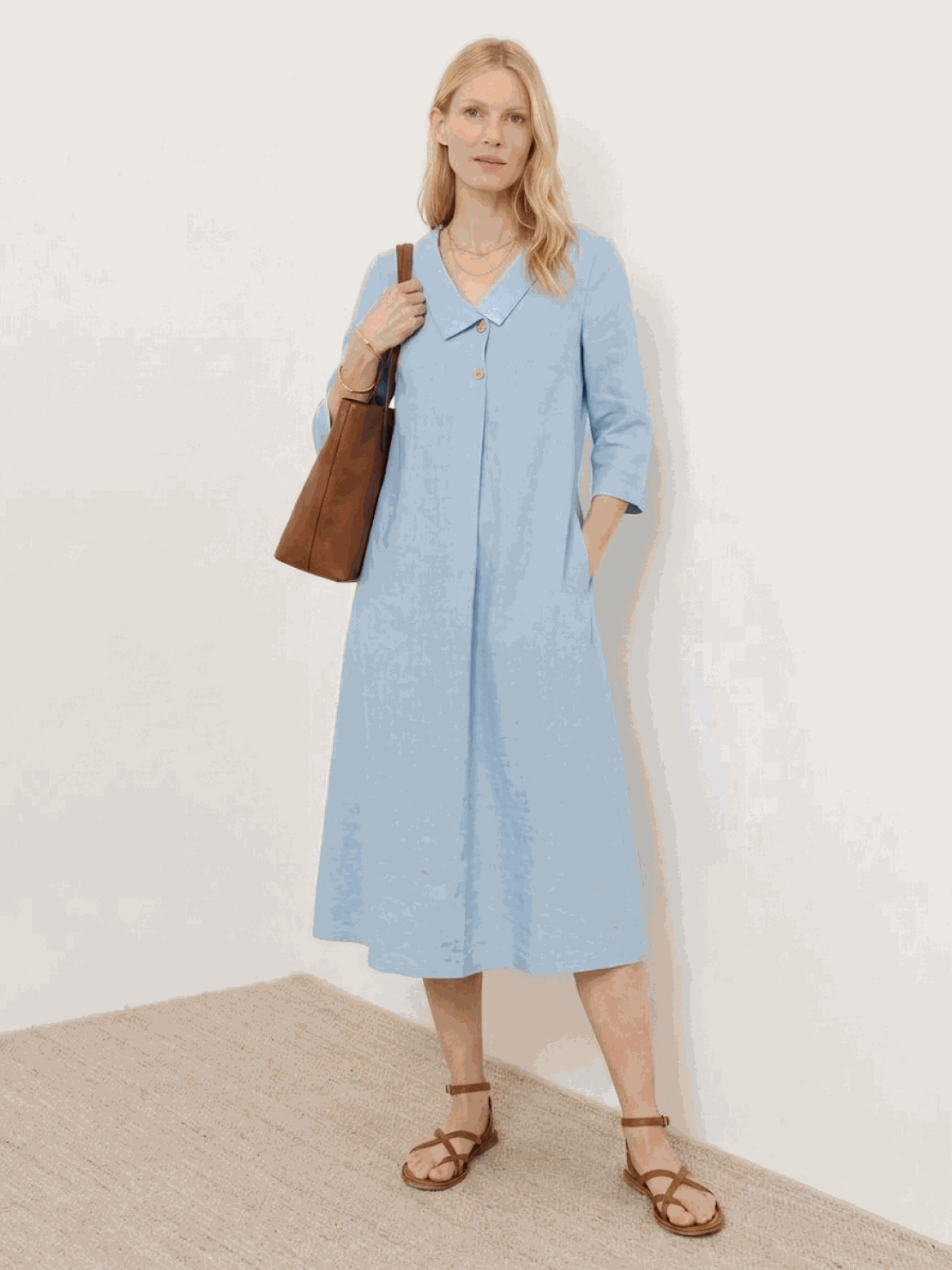 Woman wearing navy linen-look midi dress with blazer neckline and button detail standing outdoors