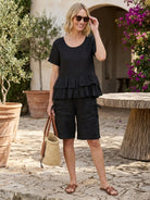 woman wearing navy blue cotton relaxed shorts and matching ruffle detail top two-piece set