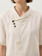 Women wearing relaxed 100% linen V-neck top with asymmetric button detail in navy, pastel pink, and cream colors