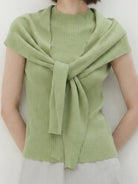 Beige knit vest with attached scarf showcasing sleeveless, ribbed knit design and versatile styling options