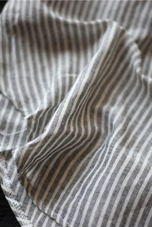 Close-up of striped linen blend fabric with gray and white stripes and gauzy texture