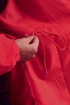 Close-up of red water resistant oversized windbreaker jacket with adjustable drawstring detail
