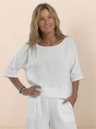 Woman wearing white short-sleeved pullover and wide trouser matching set made of cotton with a relaxed fit and deep pockets