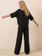 woman wearing black short-sleeved pullover and wide trouser matching set back view